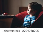 Small photo of 6 year boy attentively looking at laptop screen. Child watching horror video engrossed. Emotions of fear and horrible. Concept of useless content. Parental control. Bad effect on the psyche. Too near.