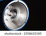 Small photo of Studio flash light bulb closeup. Spotlight studio lamp on a black background. Photoelectric technology. Flashlight equipment. Copy space. Banner. Cold temperature.