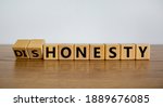 Small photo of Honesty or dishonesty symbol. Turned cube and changed the word 'dishonesty' to 'honesty'. Beautiful wooden table, white background. Business and honesty or dishonesty concept. Copy space.