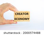 Creator economy symbol. Wooden blocks with words Creator economy on beautiful white background, copy space. Businessman hand. Business and creator economy concept.