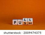 Pull or push symbol. Turned wooden cubes and changed the word 'push' to 'pull'. Beautiful orange background, copy space. Business and pull or push concept.