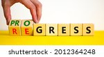 Small photo of Regress or progress symbol. Businessman turns wooden cubes and changes the word 'regress' to 'progress'. Beautiful yellow table, white background, copy space. Business, regress or progress concept.