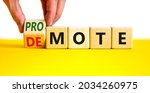 Small photo of Promote or demote symbol. Businessman turns a cube and changes the word 'demote' to 'promote'. Beautiful yellow table, white background. Business, demote or promote concept. Copy space.