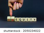 Small photo of Inequity or equity symbol. Businessman turns wooden cubes and changes the word inequity to equity. Business and inequity or equity concept. Beautiful grey background, copy space.