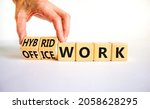 Small photo of Hybrid or office work symbol. Businessman turns cubes and changes words 'office work' to 'hybrid work'. Beautiful white background. Business, hybrid or office working concept, copy space.