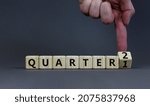 Small photo of From 1st to 2nd quarter symbol. Businessman turns a cube and changes words 'quarter 1' to 'quarter 2'. Beautiful grey table, grey background. Business, happy 2nd quarter concept, copy space.