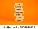 Small photo of Possible or impossible symbol. Wooden blocks with words It always seems impossible until it is done. Beautiful orange background, copy space. Business possible or impossible concept.