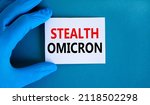 New covid-19 stealth omicron variant strain symbol. Hand in blue glove with white card. Concept words Stealth omicron. Medical and COVID-19 stealth omicron variant strain concept. Copy space.