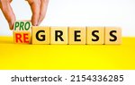 Small photo of Regress or progress symbol. Businessman turns wooden cubes and changes the word Regress to Progress. Beautiful yellow table white background. Business regress or progress concept. Copy space.