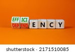 Small photo of Efficiency or dependency symbol. Turned wooden cubes and changed the word dependency to efficiency. Beautiful orange table, orange background, copy space. Business, efficiency or dependency concept.