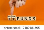 Small photo of Mutual funds vs ETF symbol. Businessman turns a cube and changes words 'ETF, Exchange-Traded Fund' to 'Mutual funds. Beautiful orange background, copy space. Business and ETF vs mutual funds concept.