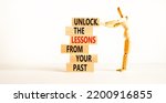 Small photo of Lessons from your past symbol. Concept words Unlock the lessons from your past on wooden blocks. Bussinesman hand. Beautiful white background. Business and lessons from your past concept. Copy space.