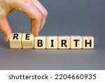 Small photo of Birth or rebirth symbol. Businessman turns wooden cubes and changes the word birth to rebirth. Beautiful grey table grey background, copy space. Business, birth or rebirth concept.