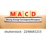 Small photo of MACD symbol. Concept words MACD moving average convergence divergence on wooden block on beautiful white background. Business MACD moving average convergence divergence concept. Copy space.