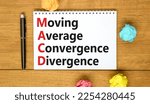 Small photo of MACD symbol. Concept words MACD moving average convergence divergence on white note on beautiful wooden background. Business MACD moving average convergence divergence concept. Copy space.