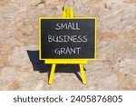 Small photo of Small business grant symbol. Concept words Small business grant on black chalk blackboard on a beautiful stone background. Business, finacial and small business grant concept.