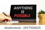 Small photo of Anything is possible symbol. Concept words Anything is possible on beautiful tablet screen. Beautiful wooden table white background. Businessman hand. Business anything possible concept. Copy space.