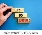 Small photo of let is do business symbol. Concept words let is do business on beautiful wooden blocks. Beautiful blue table blue background. Businessman hand. let is do business concept. Copy space.