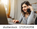 woman talking on the phone while working on computer in desk office. Searching on internet