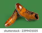 Small photo of A pair of premium calfskin boots on a green background. Horizontal shot.