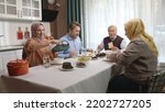 Small photo of Happy Muslim family having iftar dinner together in the kitchen. A Muslim Turkish family breaks their fast at the iftar table. Iftar is the evening meal at which Muslims
