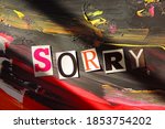   Sorry word from cut out block letters on abstract background , black and red brush strokes paint and grunge surface,   light and hard shadow dramatic effect         