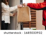 The food delivery man passes the craft package to the customer at the door of her house