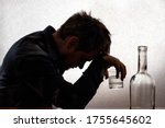 Small photo of A silhouetted photo. A man in alcoholic intoxication holds a glass of alcohol. Alcoholism, addiction, delirium.