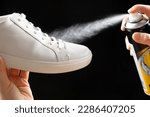 Small photo of Applying a water-repellent hydrophobic spray to white women's sneakers. Protection of shoes from moisture, dirt and unpleasant odor