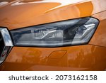 Front edgy car LED headlight. Detail of headlamp with headlight washer. Orange shiny car. Close up. 