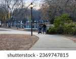 a shot of a smooth winding concrete footpath in the park surrounded by gorgeous autumn colored trees with people walking on the path at Freedom Park in Charlotte North Carolina USA	
