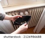 Heating bill. Increase in the cost of gas bill. Soaring energy prices. Increase in the price of natural gas. Energy crisis in Europe. Hands hold wallet with money near the radiator. Pay the bills.