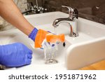 Small photo of The hands of a man in blue nitrile rubber gloves wash the clean white sink in the bathroom.Orange sponge washcloth with foam in water.Cleaning dirty plumbing at home.Cleaning service concept with supp