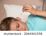 Small photo of Teen boy with otitis and earaches holding drops for treatment. Kid suffering from otitis. Acute ear pain, inflammatory disease of the middle ear