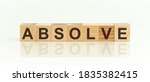 Small photo of Wooden Blocks with the text: Absolve.. The text is written in black letters and is reflected in the mirror surface of the table. New business relaunch startup concept.