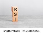 wooden cube on a white table with text RSI. concept of business, financial, investment, economy. copy space on right for you design, gray background. RSI - short for Relative Strength Index