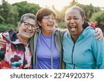 Small photo of Happy multiracial senior women having fun together outdoor - Elderly generation people hugging each other at city park with sunrise in the background