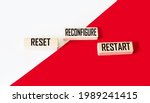 Small photo of Reset. Reconfigure. Restart text on wood blocks and red and white background