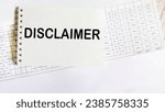 Small photo of Notepad with disclaimer text lying on documents and white background