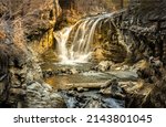 A small waterfall in the mountain cave. Cave waterfall cascade. Waterfall cascade into the cave. Cave waterfall view