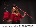 Small photo of Female magician with box and magic cane makes with soap bubbles show, an illusionist in theatrical clothes and hat. Woman actress in stage costume. Concept of theatrical performance and fun show
