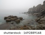 rocky shore in the fog, stones sticking out of the water