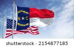 Small photo of The North Carolina state flag waving along with the national flag of the United States of America. North Carolina is a state in the Southeastern region of the United States