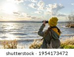 Young woman looking through binoculars at birds on the lake. Birdwatching, zoology, ecology. Research in nature, observation of animals. Ornithology