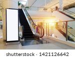 blank showcase billboard or advertising light box for your text message or media content with escalator in modern department store shopping mall, shopping center, commercial and marketing concept