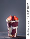 Small photo of Brazilian frozen acai in a plastic cup with condensed milk and strawberry. Fruit from the Amazon. Copy space