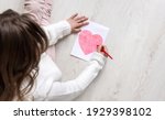 A little girl draws a heart on...