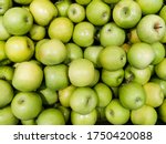 Solid background of green apples in a crate. Many organic Granny Smith apples. Healthy and affordable fruits in the supermarket, source of vitamin C. Pattern for design. View from above.