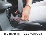 Close-up of a woman's hand fastening a seat belt in a car. Woman driver fastens her seat belt before driving. Driving safety concept.