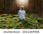Woman sitting in forest enjoys the silence and beauty of nature.